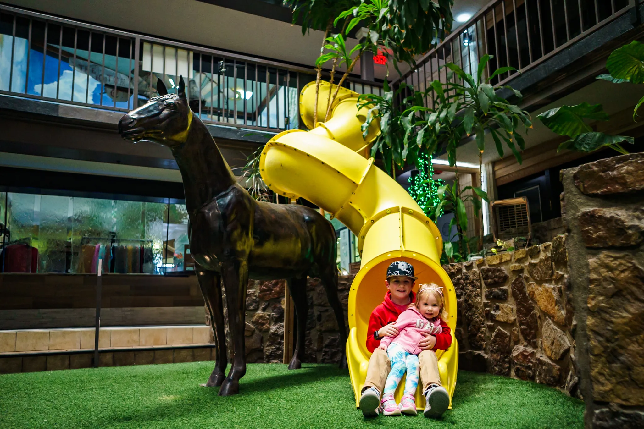 The two-story indoor slide beside the bronze horse