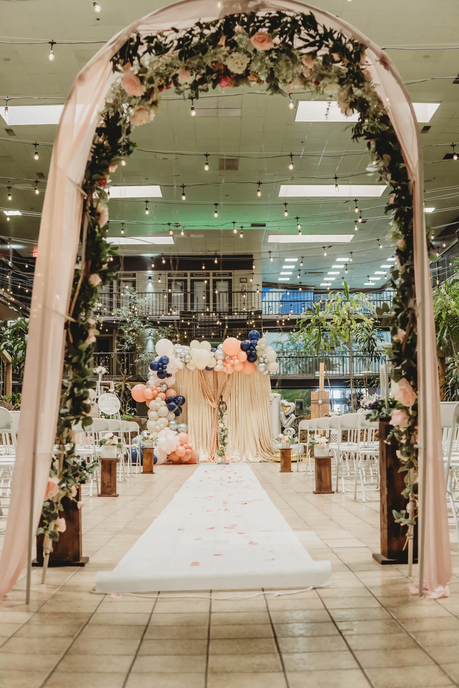 A floral wedding arch over the atrium aisle
