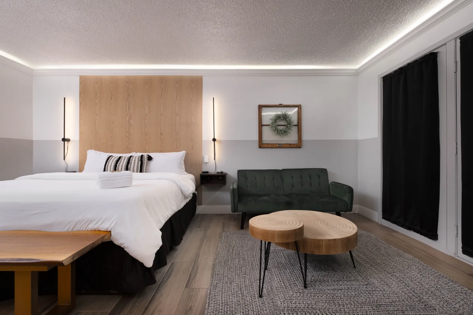 A Deluxe King room with a wood-slat headboard and a green velvet sofa