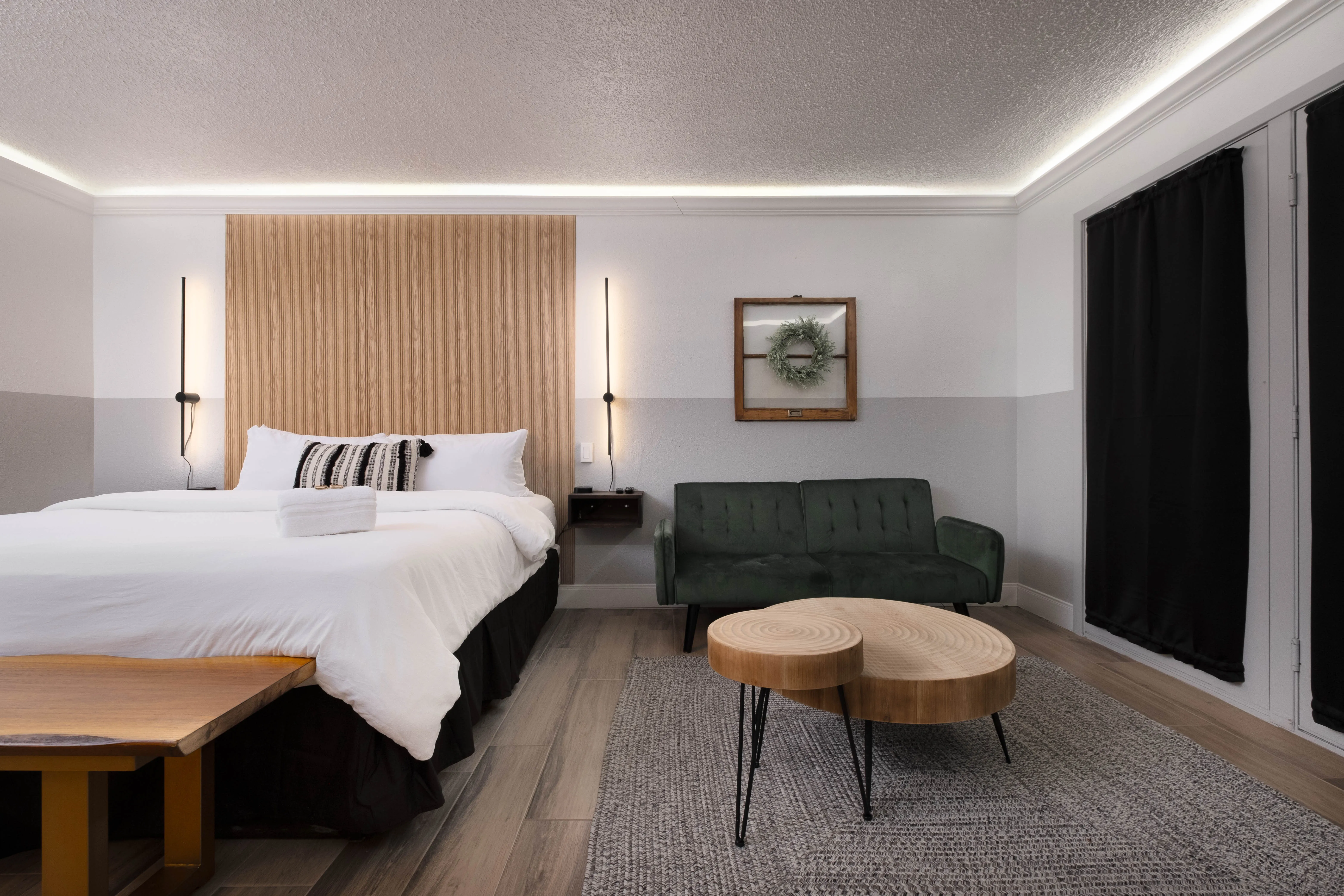 Deluxe king room with wood-slat headboard and green velvet sofa