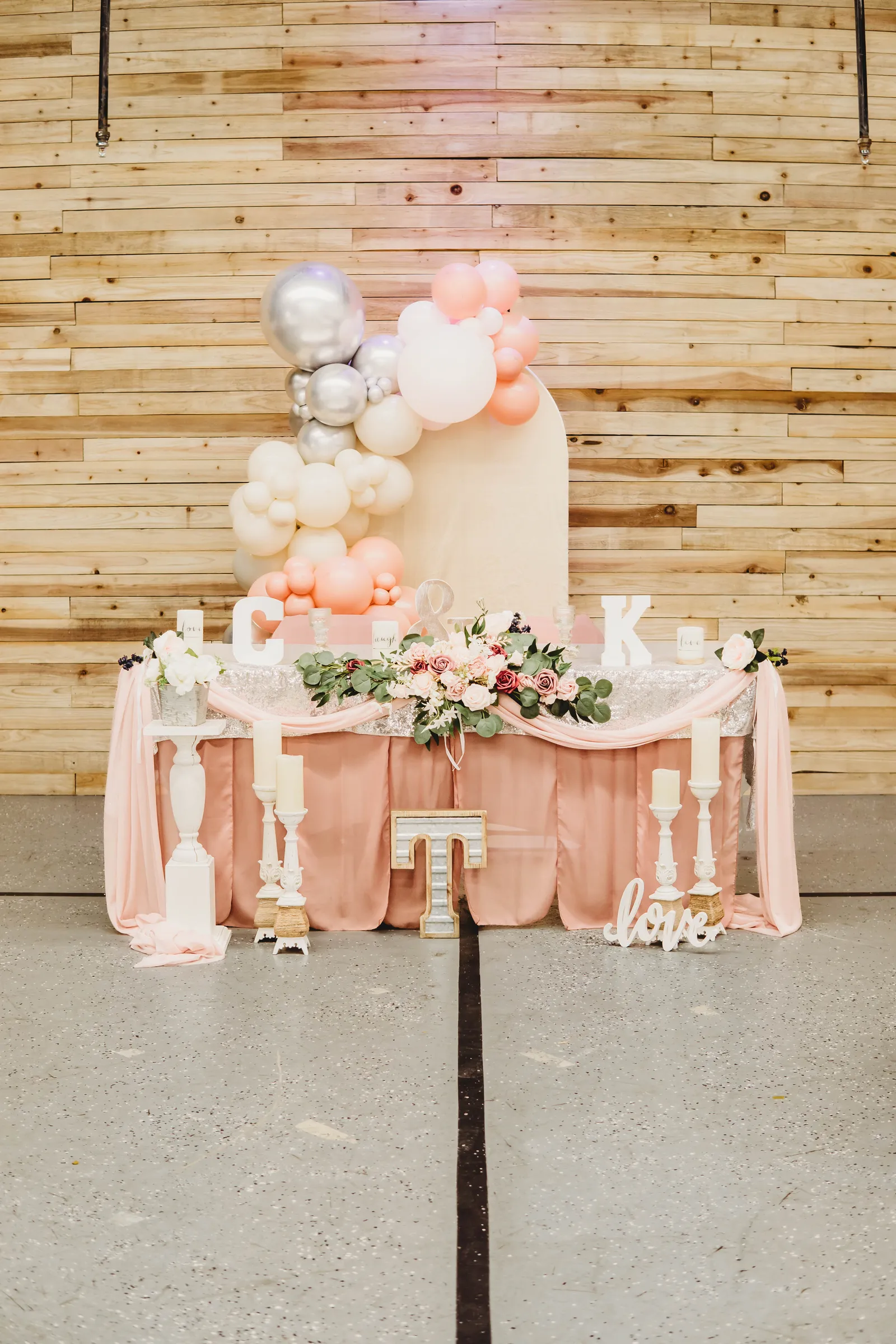 A styled sweetheart table with balloon garland in the banquet hall